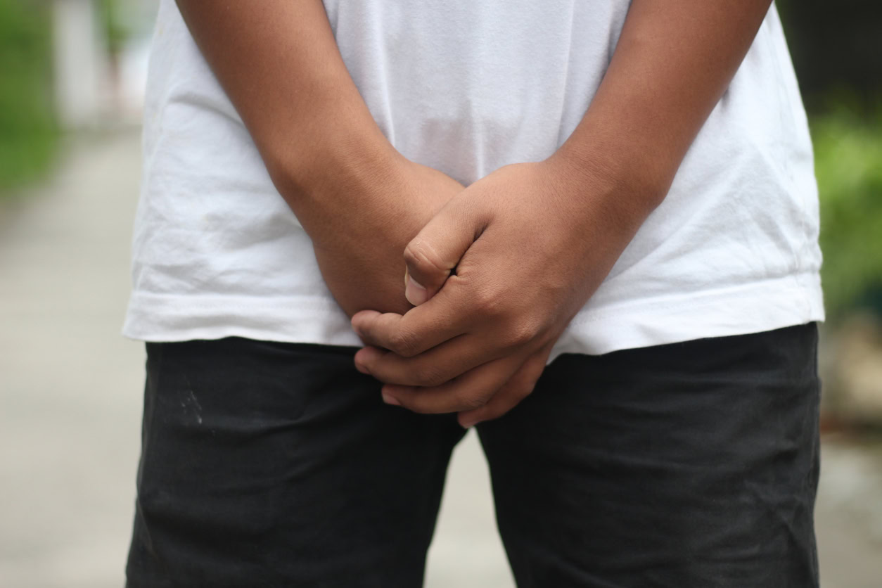 Close up of a man with hands holding his crotch