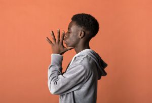 Calm young black guy with standing in orange studio win closed eyes